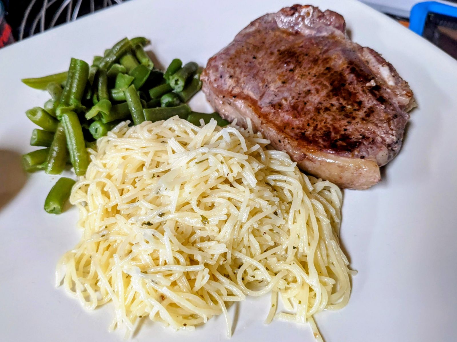 garlic parmesan pasta with steak and green beans on a white plate