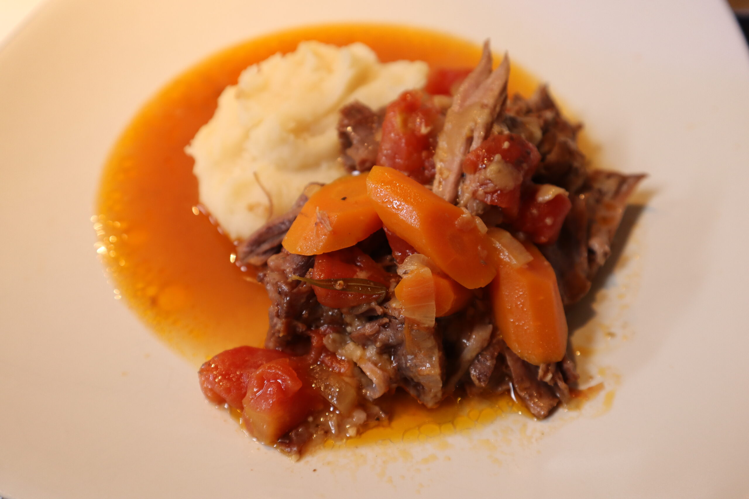 Osso Buco served with mashed potatoes on a white plate.