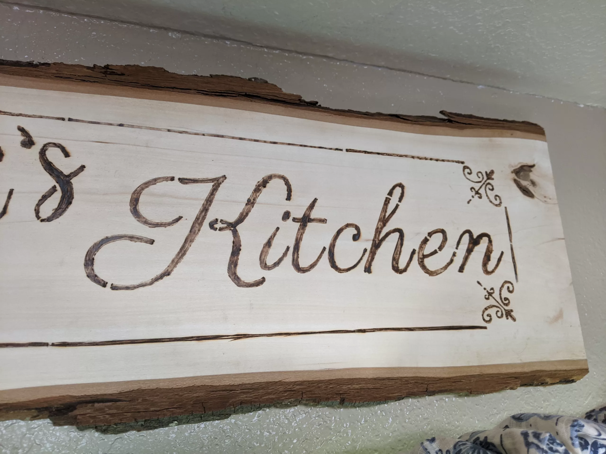 wood plank with live edge and border with word kitchen written with wood burning kit