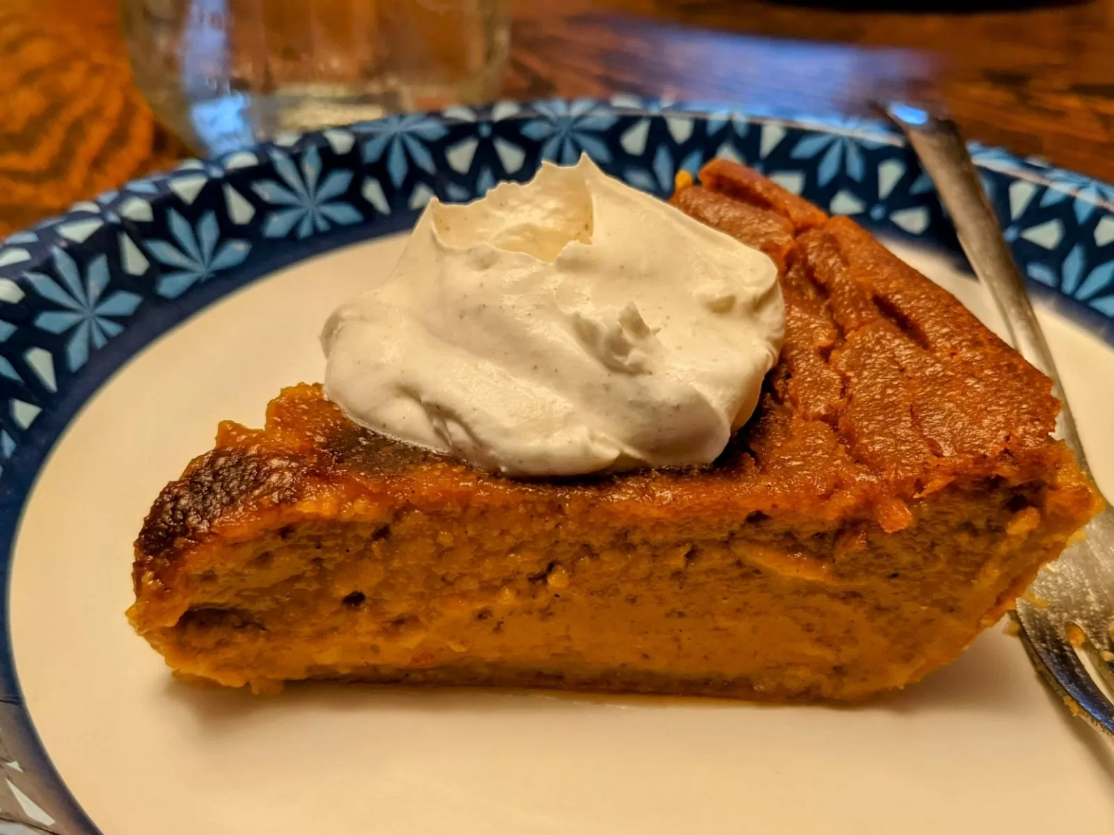 slice of sweet potato pie with whipped cream on a paper plate