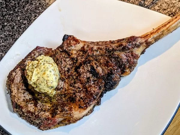 tomahawk steak with butter compound on a white plate