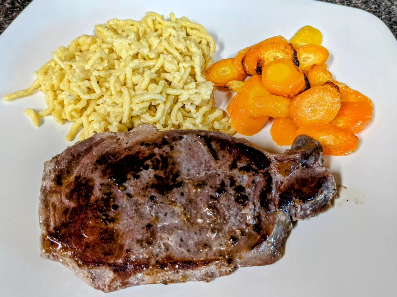 german spaetzle, roasted carrots, and steak on a plate